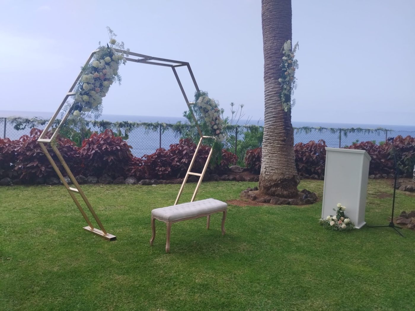 Arco hexagonal, banco y atril de ceremonia junto a una palmera