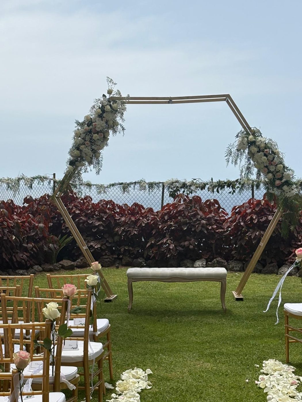 Arco floral, banco y sillas doradas con rosas