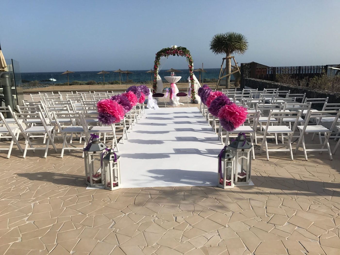 Arco de ceremonia con flores rosas y moradas en la playa