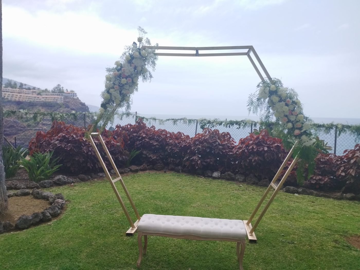 Arco hexagonal floral con banco y vistas al mar