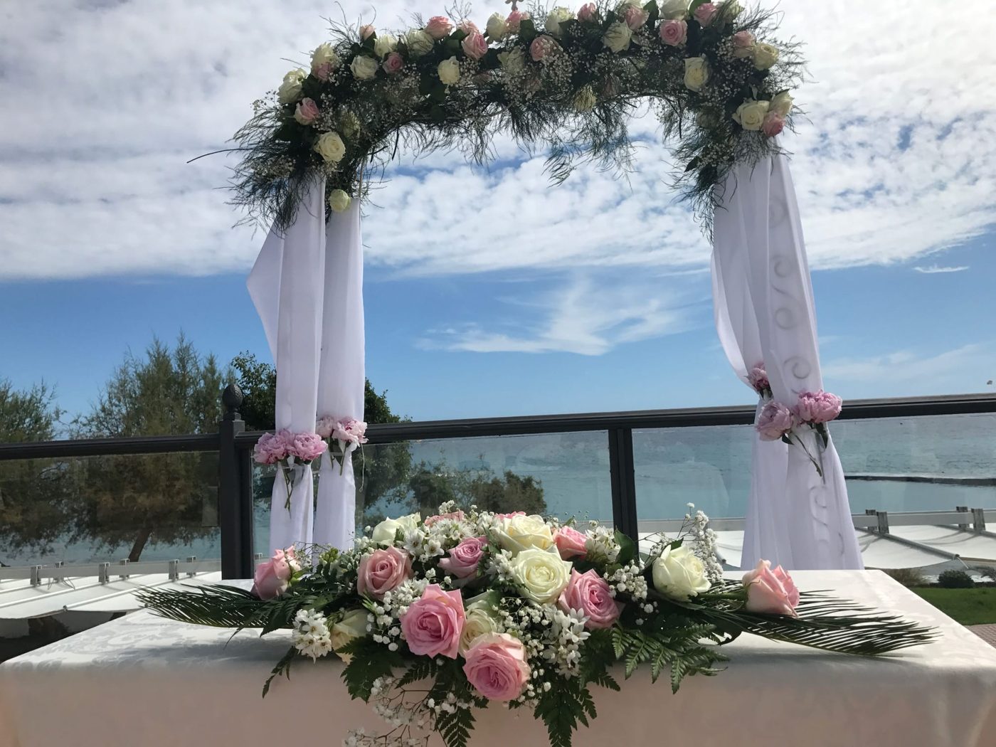 Arco con rosas blancas y rosadas sobre una mesa de ceremonia