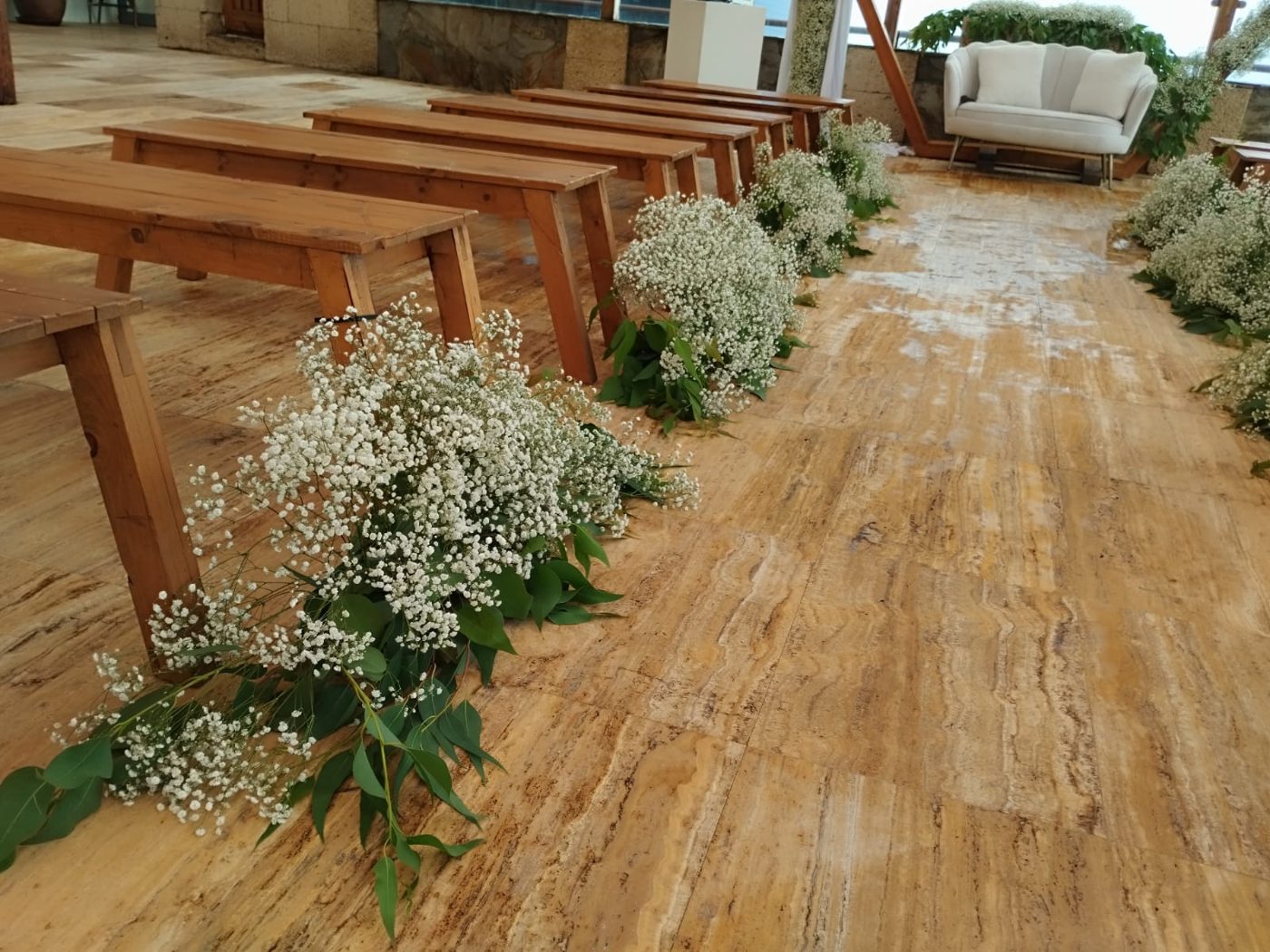 Pasillo de mesas de madera decoradas con flores