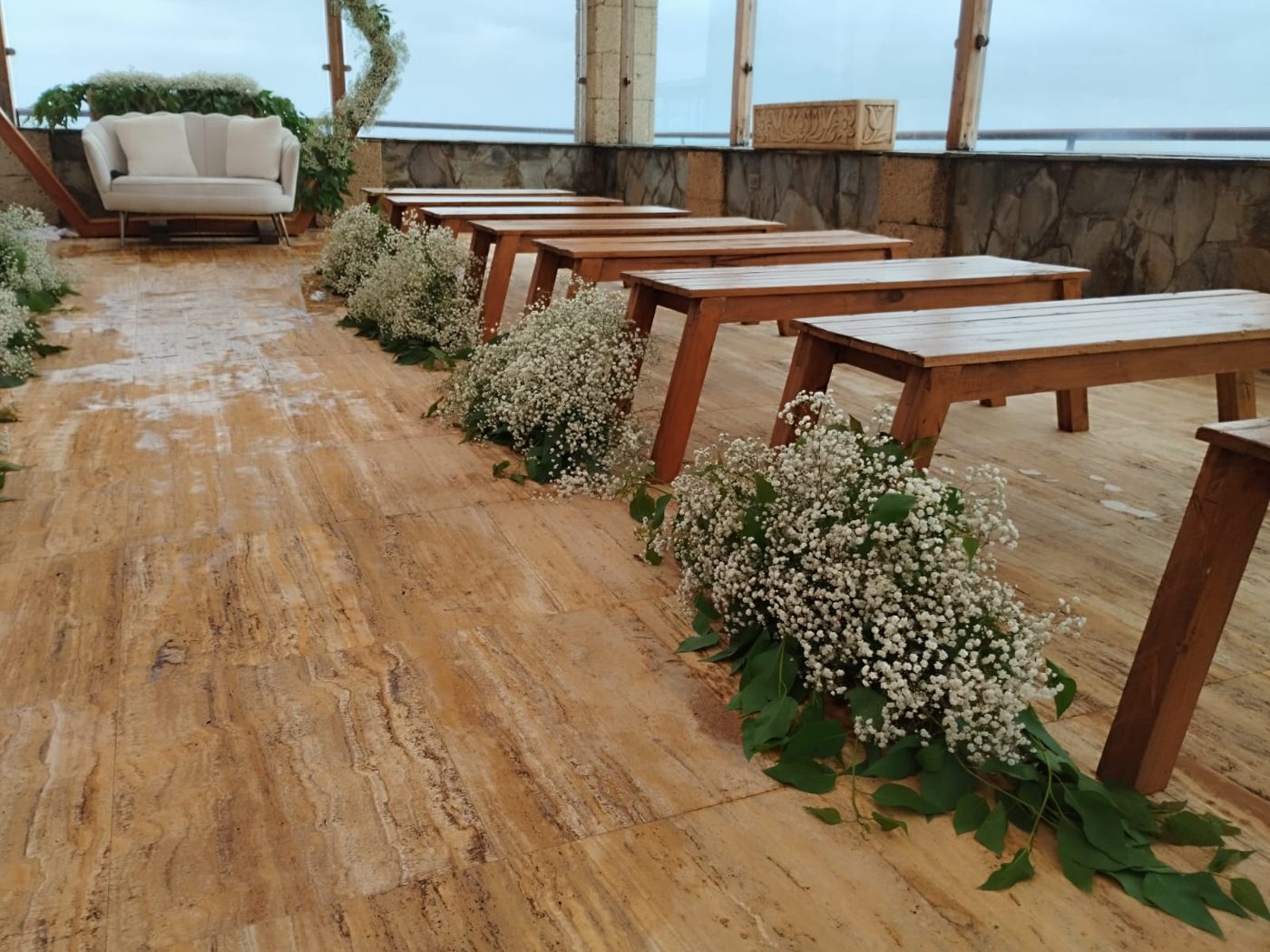 Mesas de madera con flores en terraza con vistas al mar