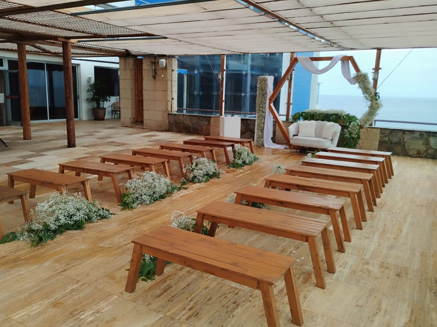 Mesas de madera en terraza junto al arco con vistas al mar