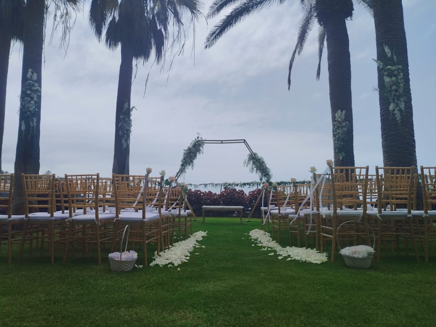 Sillas doradas de ceremonia con arco hexagonal entre palmeras