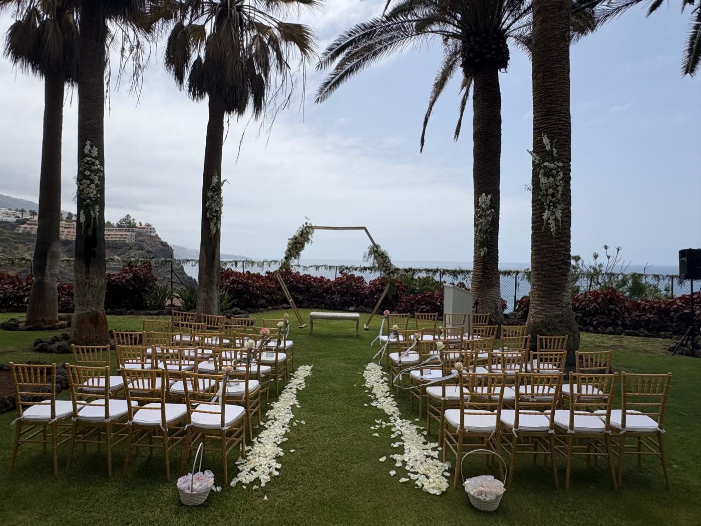 Sillas doradas de ceremonia con arco floral y vistas al mar
